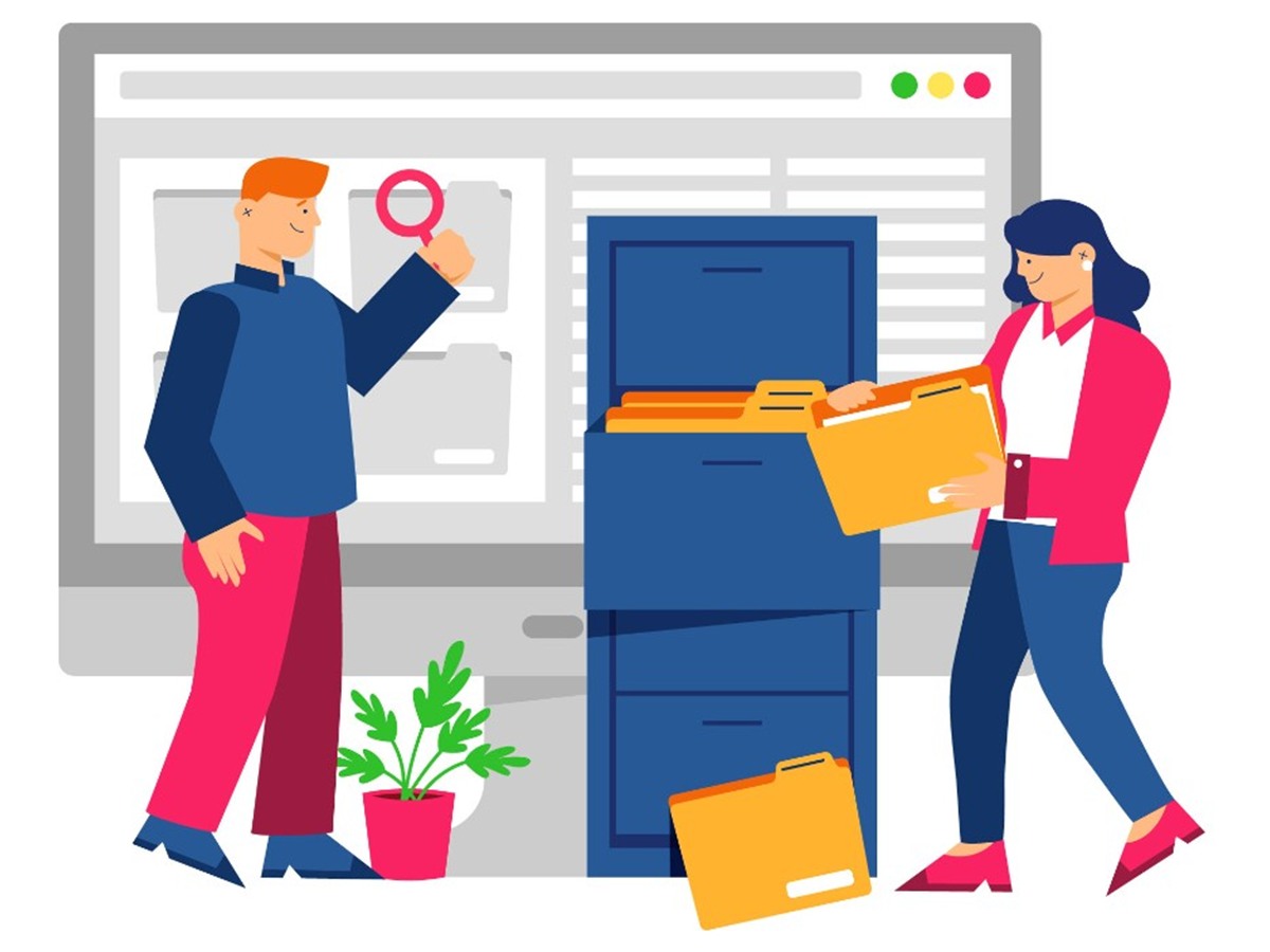 Two people organizing files beside a computer